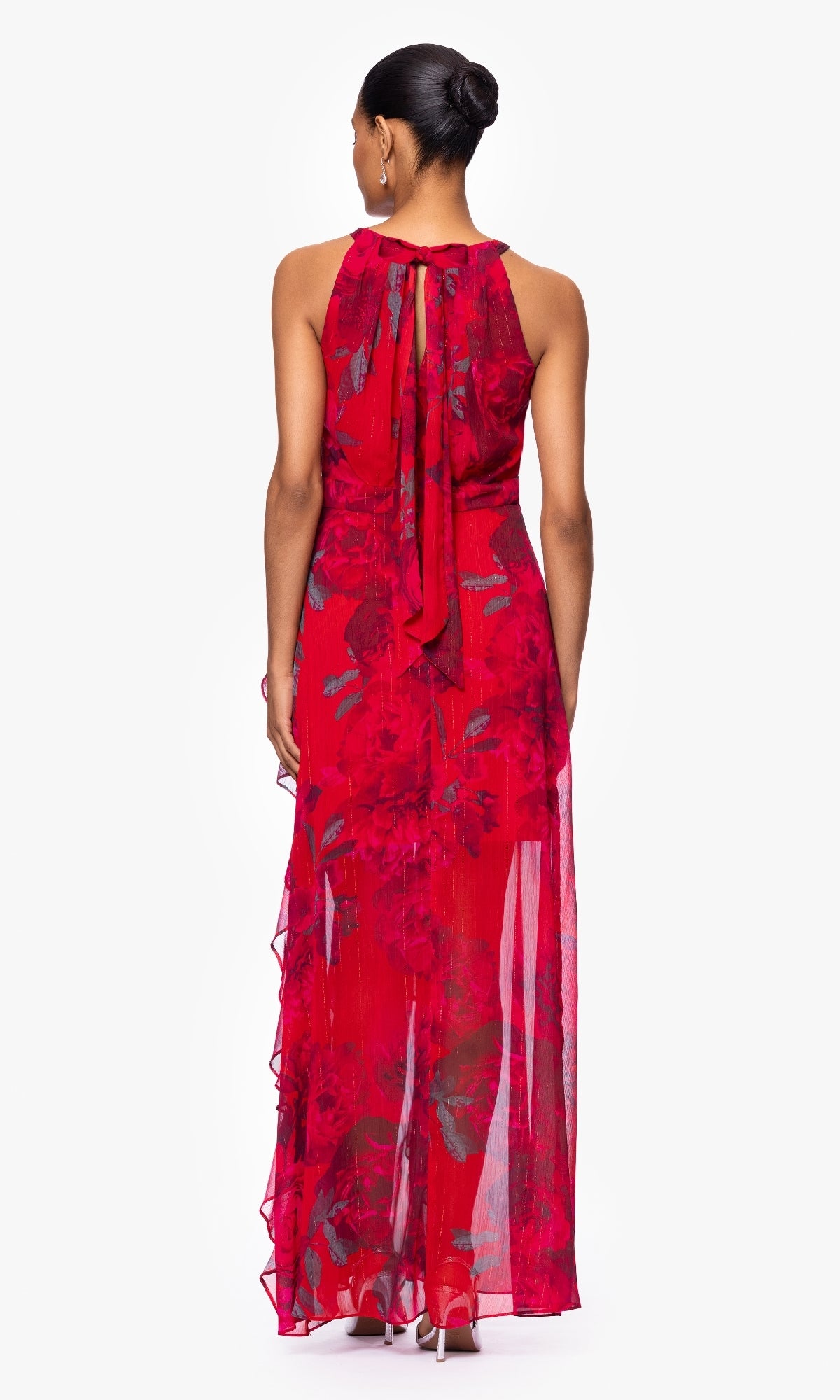 A woman faces away, wearing the Betsy & Adam A27036 long red floral formal dress with a sheer overlay and back bow detail.